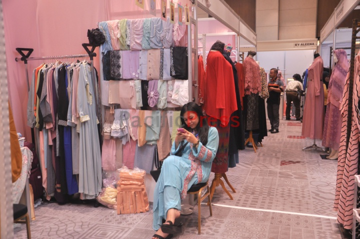A booth keeper checks her phone at Indonesia Moslem Fashion Expo. Muslim fashion Industry grows very fast in Indonesia in the past several years. As common fashion, Muslim clothing is changing consistently. Every year, there are many new designers and brands come.